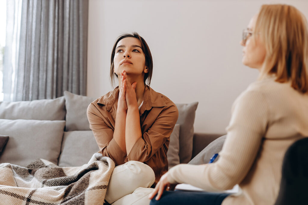 distressed woman sits on a couch and asks therapist what is dmt