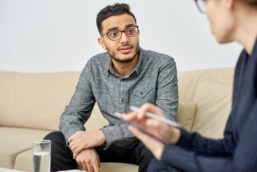 a man sitting on a couch with a man holding a pen