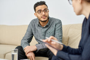 a man sitting on a couch with a man holding a pen
